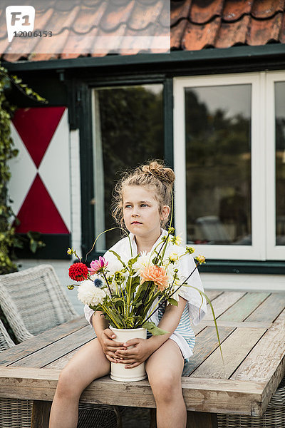 Mädchen mit Blumenstrauß auf dem Terrassentisch