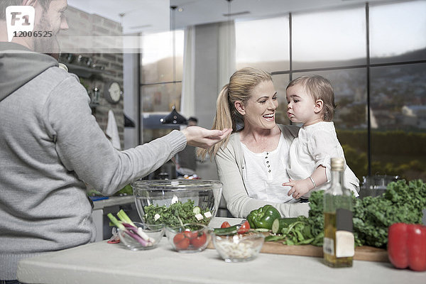 Familie mit Baby bei der Zubereitung einer gesunden Mahlzeit in der Küche