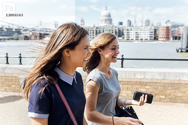 Großbritannien  London  zwei Frauen  die am Ufer der Themse spazieren gehen.