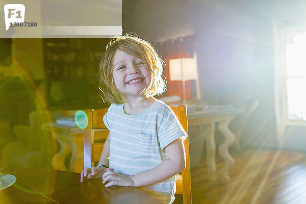 Sonnenschein auf einem kaukasischen Jungen  der am Tisch sitzt