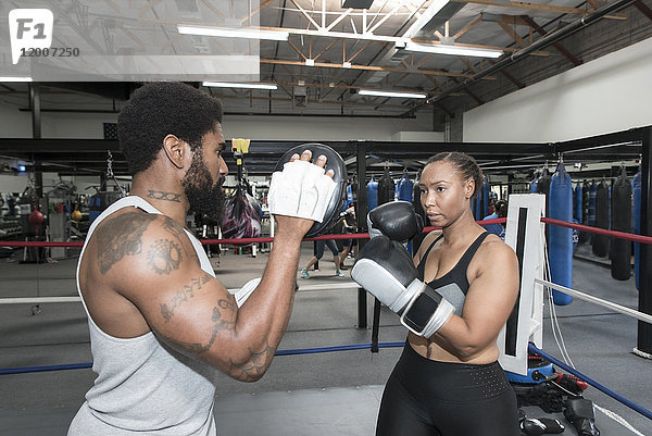 Schwarze Frau beim Sparring mit Trainer im Boxring