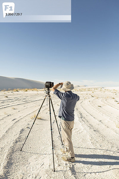 Kaukasischer Fotograf mit Stativ in der Wüste