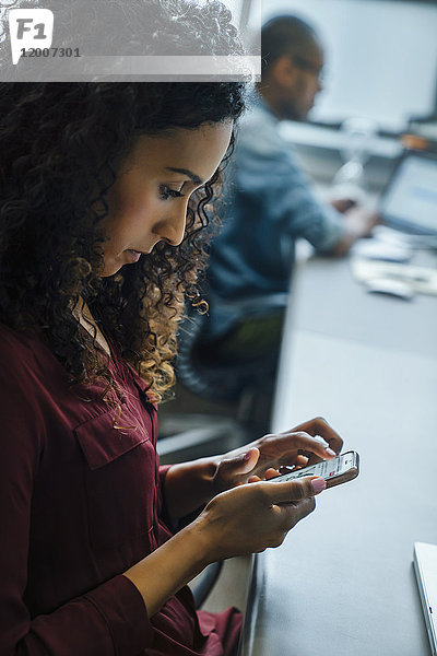 Geschäftsfrau benutzt Mobiltelefon im Büro