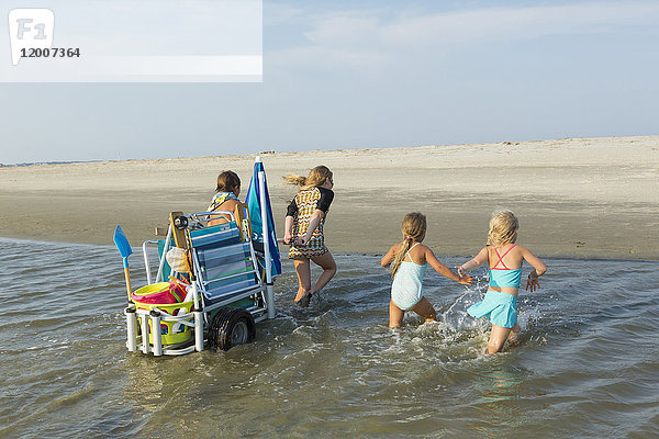 Kaukasischer Junge und Mädchen  die einen Wagen am Strand ziehen