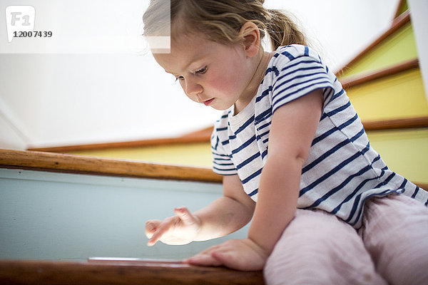 Kaukasisches Mädchen benutzt digitales Tablet auf einer Treppe