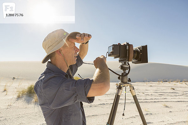 Kaukasischer Fotograf mit Stativ und Augenschutz in der Wüste