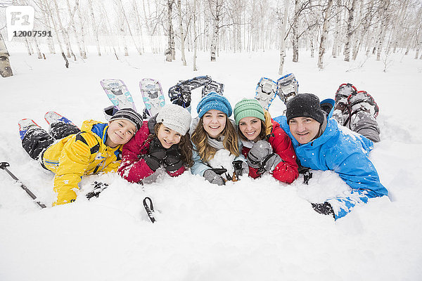 Porträt einer lächelnden kaukasischen Familie  die im Schnee liegt