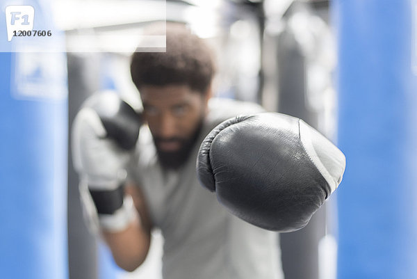 Porträt eines schwarzen Mannes mit Boxhandschuhen in einer Sporthalle