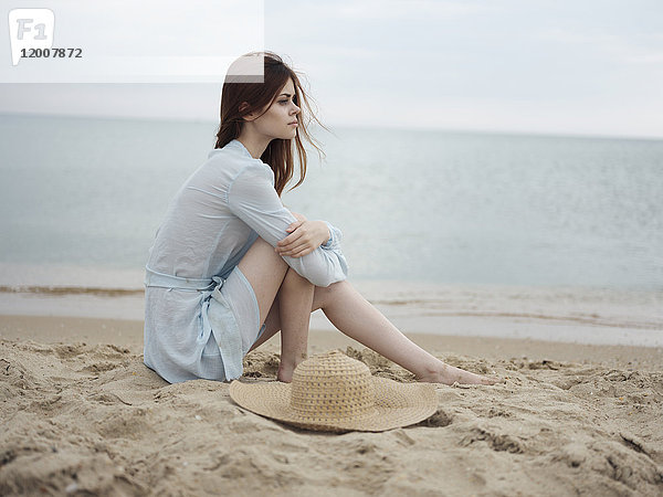 Nachdenkliche kaukasische Frau sitzt am Strand