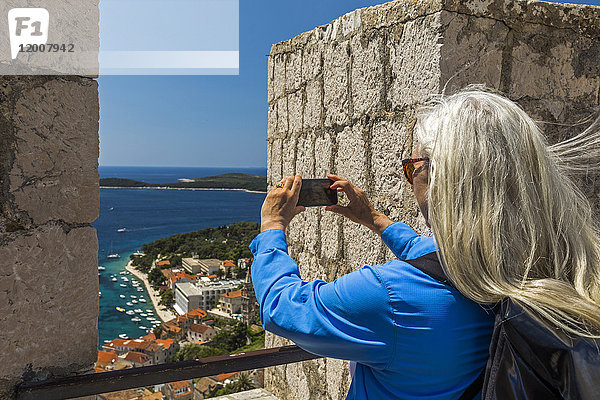 Kaukasische Frau fotografiert malerische Aussicht auf das Meer