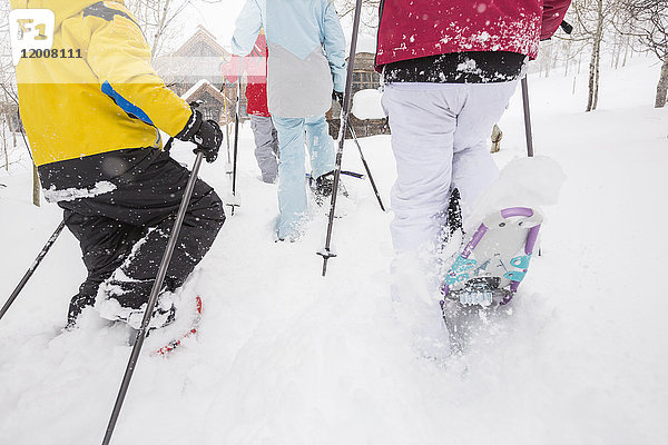 Rückansicht einer kaukasischen Familie beim Schneeschuhwandern