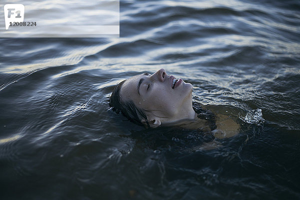 Kaukasische Frau schwimmt mit geschlossenen Augen im Meer