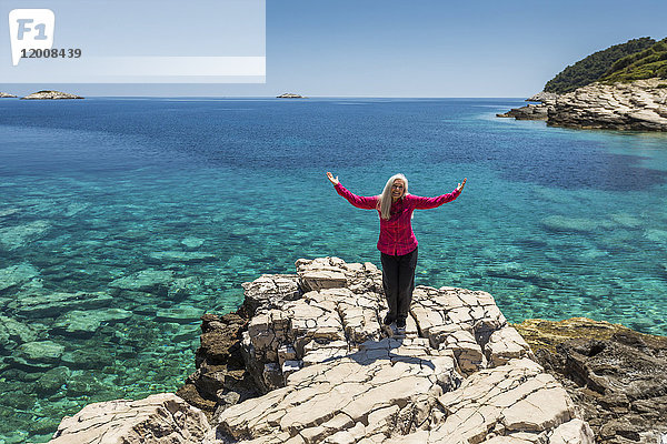 Kaukasische Frau posiert auf einem Felsen am See