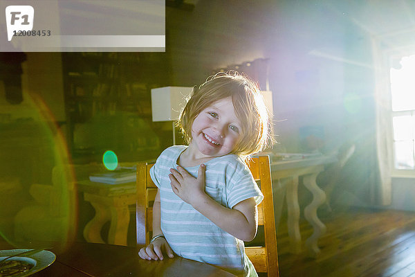 Sonnenschein auf einem kaukasischen Jungen  der am Tisch sitzt