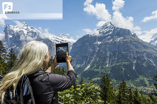 Kaukasische Frau fotografiert Berg mit digitalem Tablet