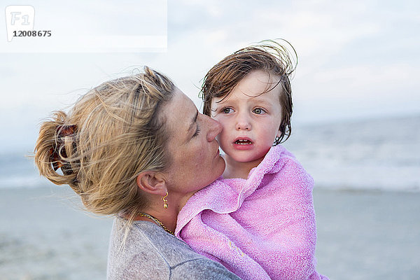 Kaukasische Mutter hält ihren Sohn am Strand