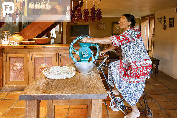 Frau tritt in die Pedale  um die Kaffeemühle in der Küche anzutreiben