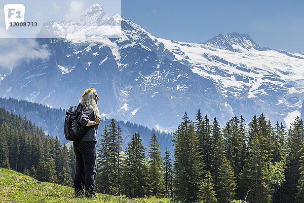 Kaukasische Frau mit Blumenkranz bewundert malerische Aussicht auf einen Berg