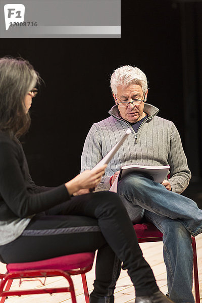 Hispanischer Mann und Frau lesen Drehbücher auf einer Theaterbühne