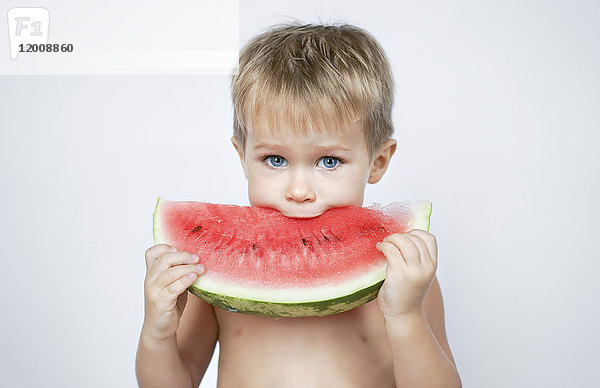 Kaukasischer Junge beißt in eine Wassermelonenscheibe