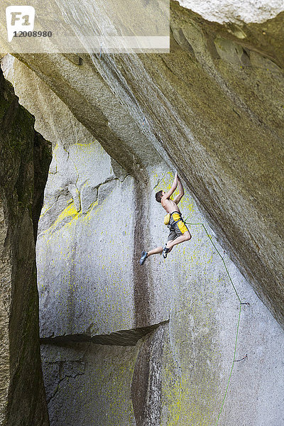 Gemischtrassiger Junge hängt an einem Felsen