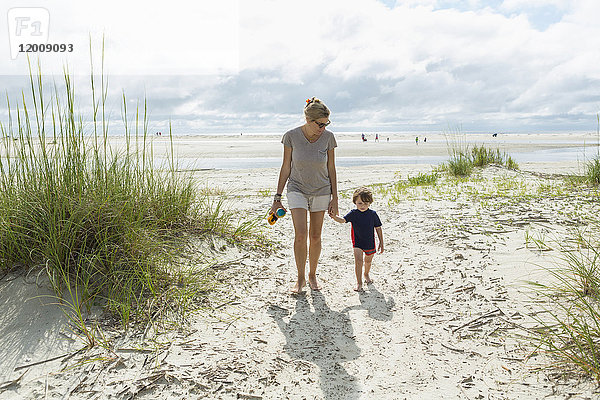 Kaukasische Mutter und Sohn gehen am Strand spazieren