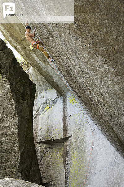 Gemischtrassiger Junge klettert auf Felsen