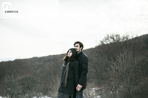 Kaukasisches Paar steht auf einem Hügel und entspannt sich