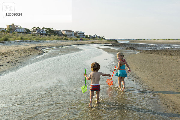 Kaukasischer Bruder und kaukasische Schwester tragen Netze am Strand