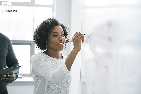Geschäftsfrau schreibt in einer Besprechung auf ein Whiteboard