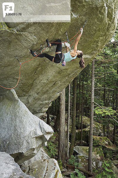 Gemischtrassiges Mädchen klettert auf Felsen