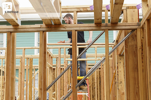Kaukasischer Mann steht auf einer Leiter auf einer Baustelle