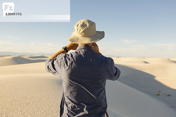 Kaukasischer Mann beim Fotografieren einer Wüstenlandschaft