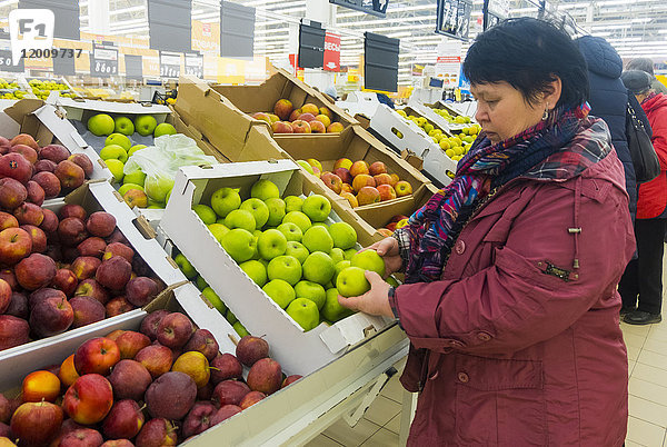 Kaukasische Frau  die Äpfel untersucht