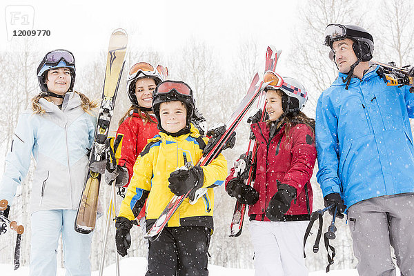 Lächelnde kaukasische Familie mit Skiern im Schnee