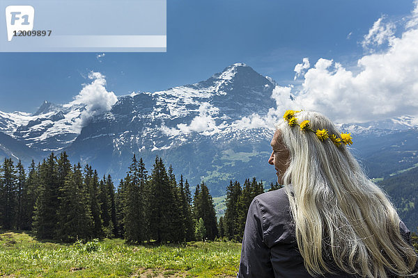 Kaukasische Frau mit Blumenkranz in der Nähe von Bergen