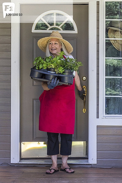 Kaukasische Frau hält Topfpflanzen in der Tür