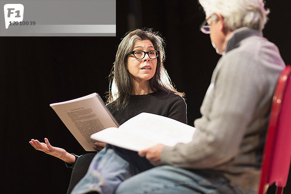 Hispanischer Mann und Frau lesen Drehbücher auf einer Theaterbühne