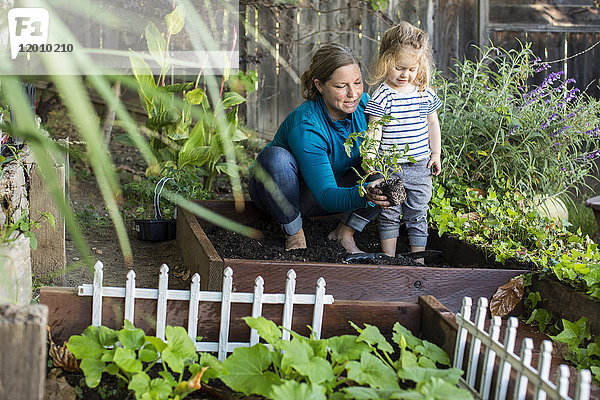 Kaukasische Mutter bringt ihrer Tochter Gartenarbeit bei
