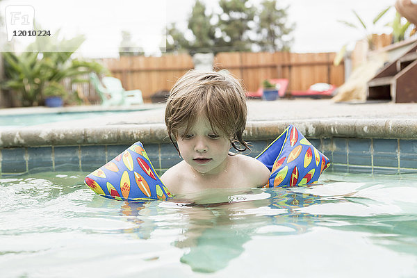 Kaukasischer Junge mit Schwimmflügeln im Schwimmbad