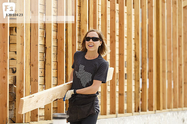 Kaukasische Frau trägt Holz auf einer Baustelle