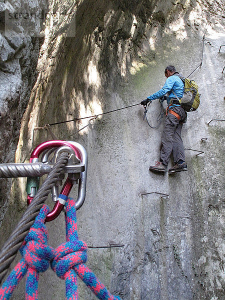 Norditalien  Trentino  Arco  Klettersteig des Flusses Sallagoni  ein Mann in einem Klettergurt klettert auf einen Felsen  der mit einem Klettersteig ausgestattet ist