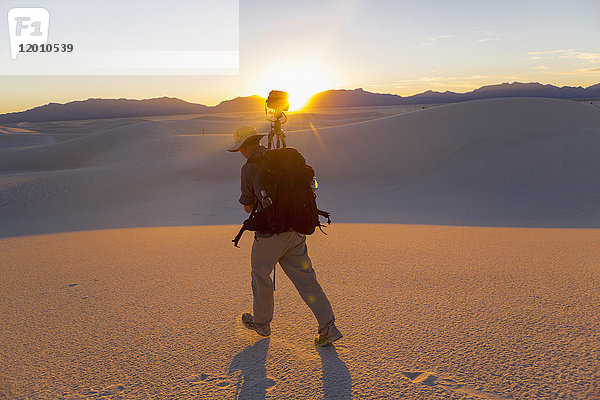 Kaukasischer Mann mit Kamera und Stativ in der Wüste