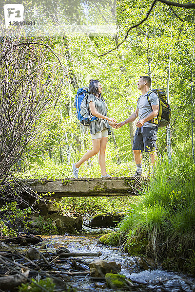 Paar trägt Rucksäcke über eine Brücke im Wald