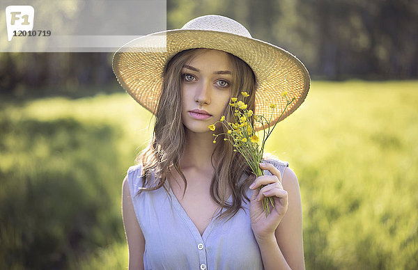Kaukasische Frau mit Hut und Wildblumen