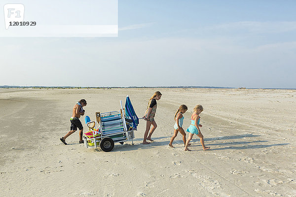 Kaukasischer Junge und Mädchen  die einen Wagen am Strand ziehen