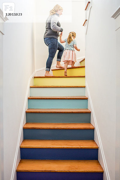 Kaukasische Mutter und Tochter klettern mehrfarbige Treppe