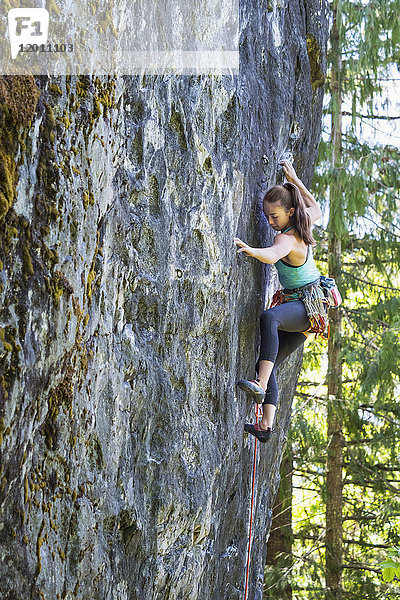 Gemischtrassiges Mädchen klettert auf Felsen