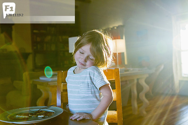 Sonnenschein auf kaukasischem Jungen beim Essen am Tisch