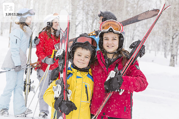 Porträt eines lächelnden kaukasischen Geschwisterpaares mit Skiern